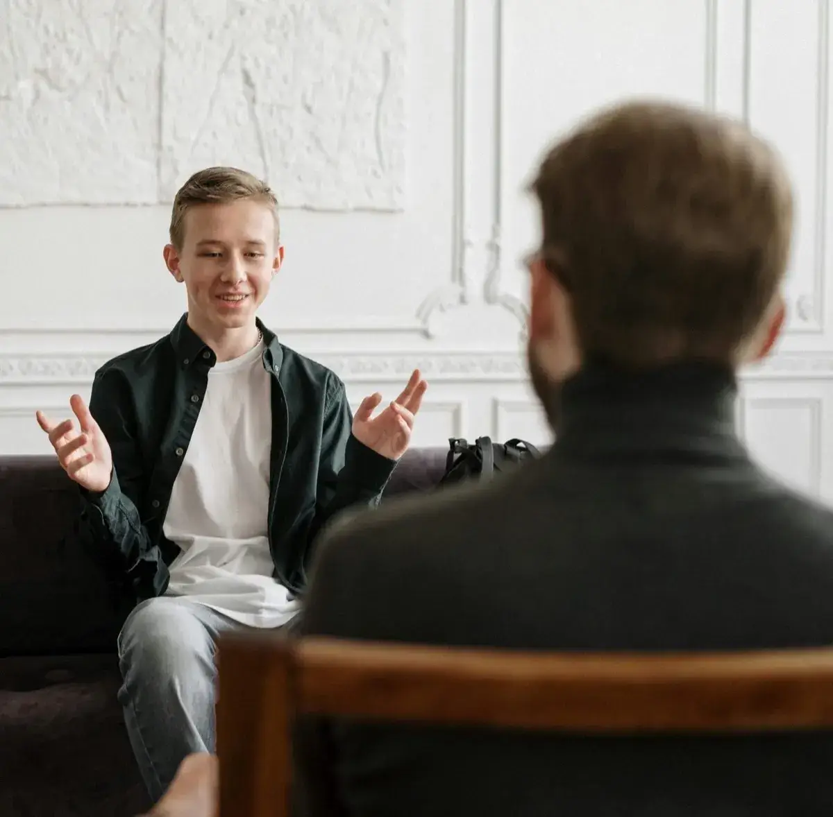 Un adolescent échange en consultation avec un psychologue, assis face à lui.